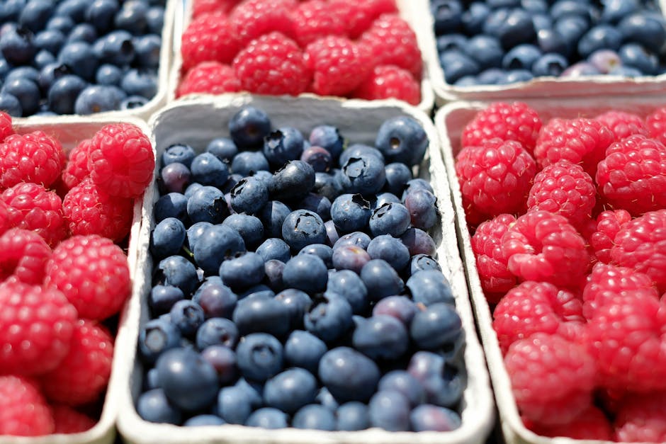 Close-up of ripe blueberries and raspberries in market baskets, showcasing fresh summer fruits.